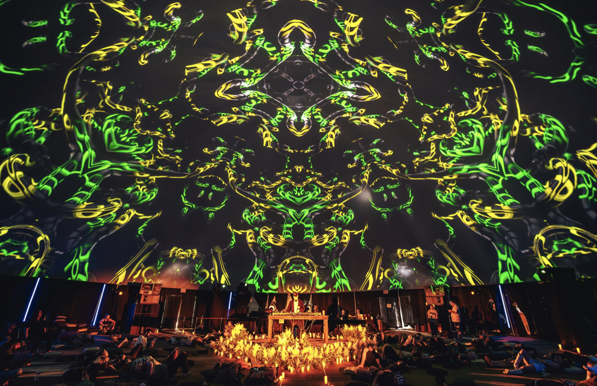 Dome ceremony with green and yellow swirling projection over candle altar